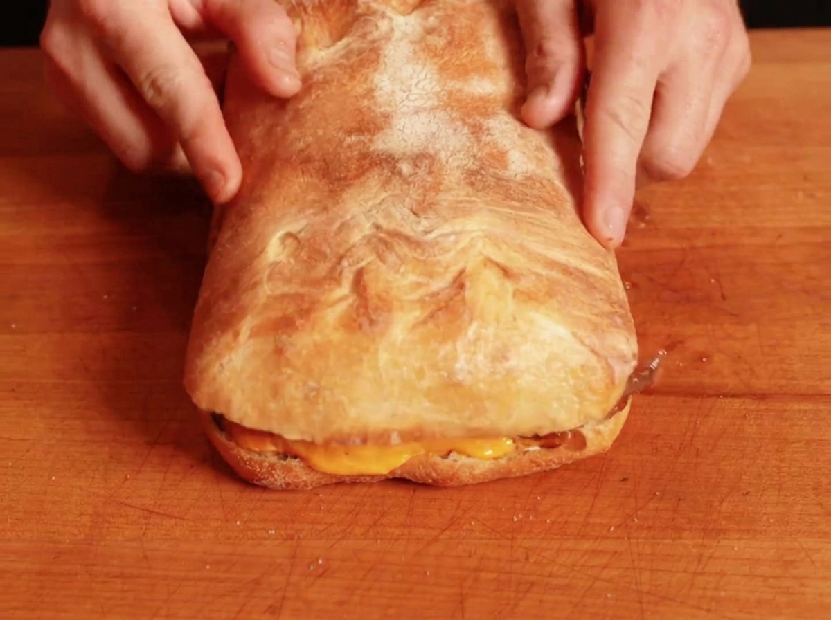 La partie supérieure du pain placée sur le sandwich garni pour compléter lassemblage.