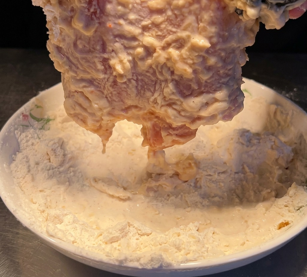Le poulet mouillé pressé à nouveau dans la farine.