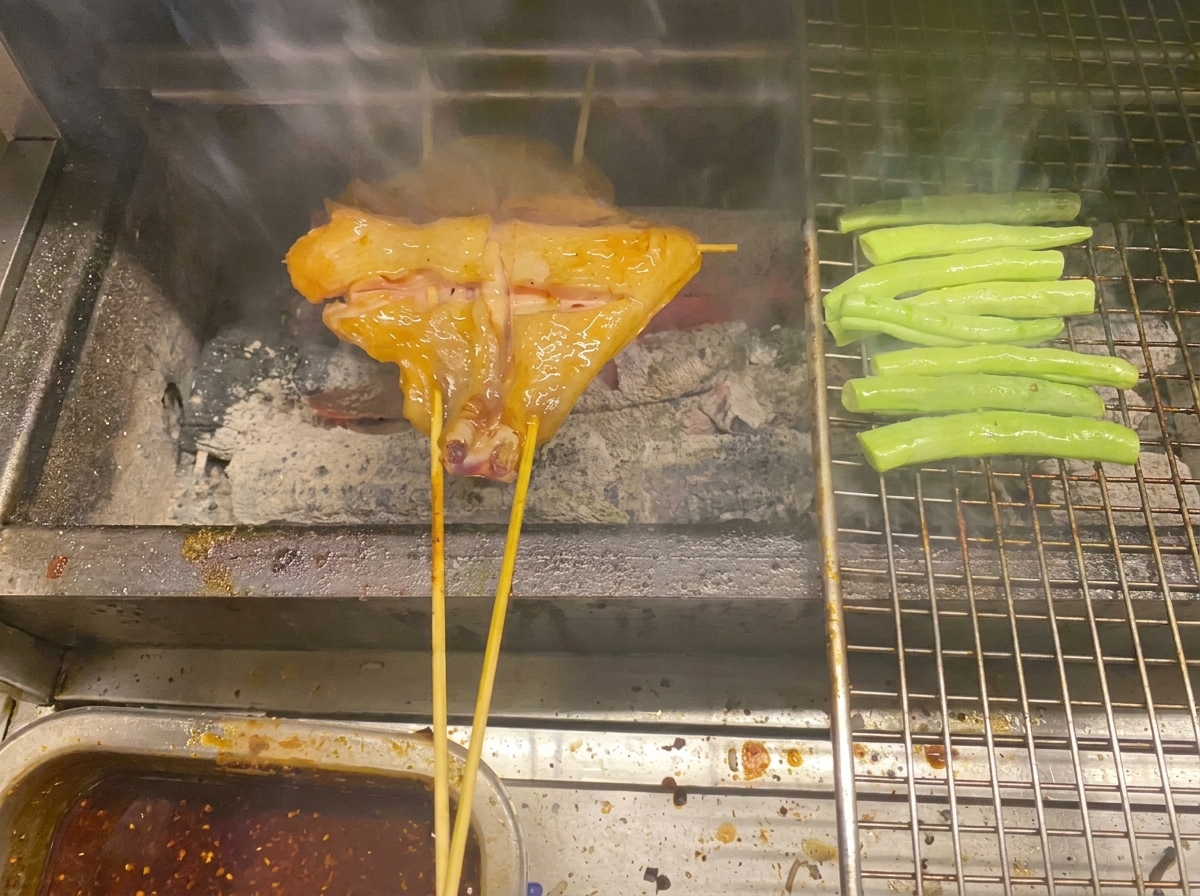 Poulet en brochette et haricots verts cuisant sur un barbecue au charbon de bois.