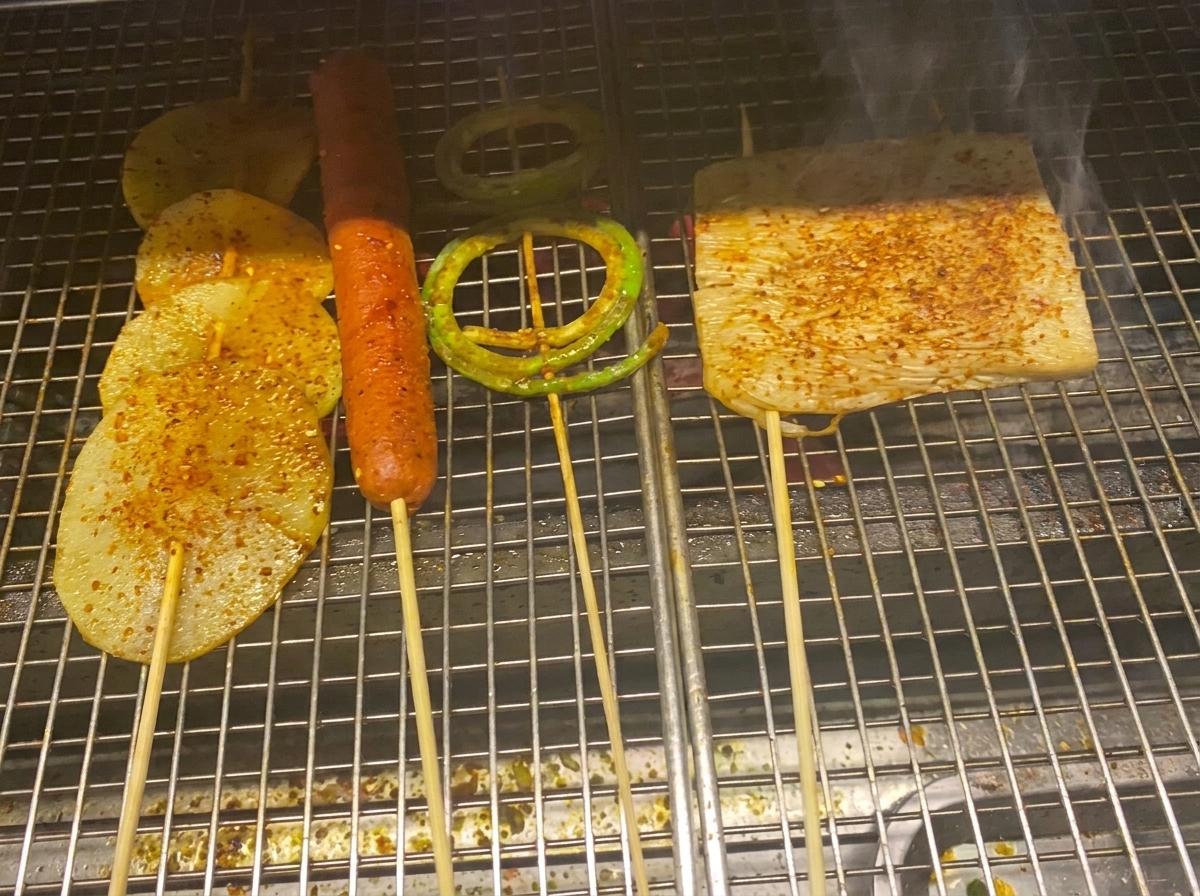 Tranches de pomme de terre, saucisse et légumes grillés nappés dune sauce barbecue brillante et de flocons de piment.