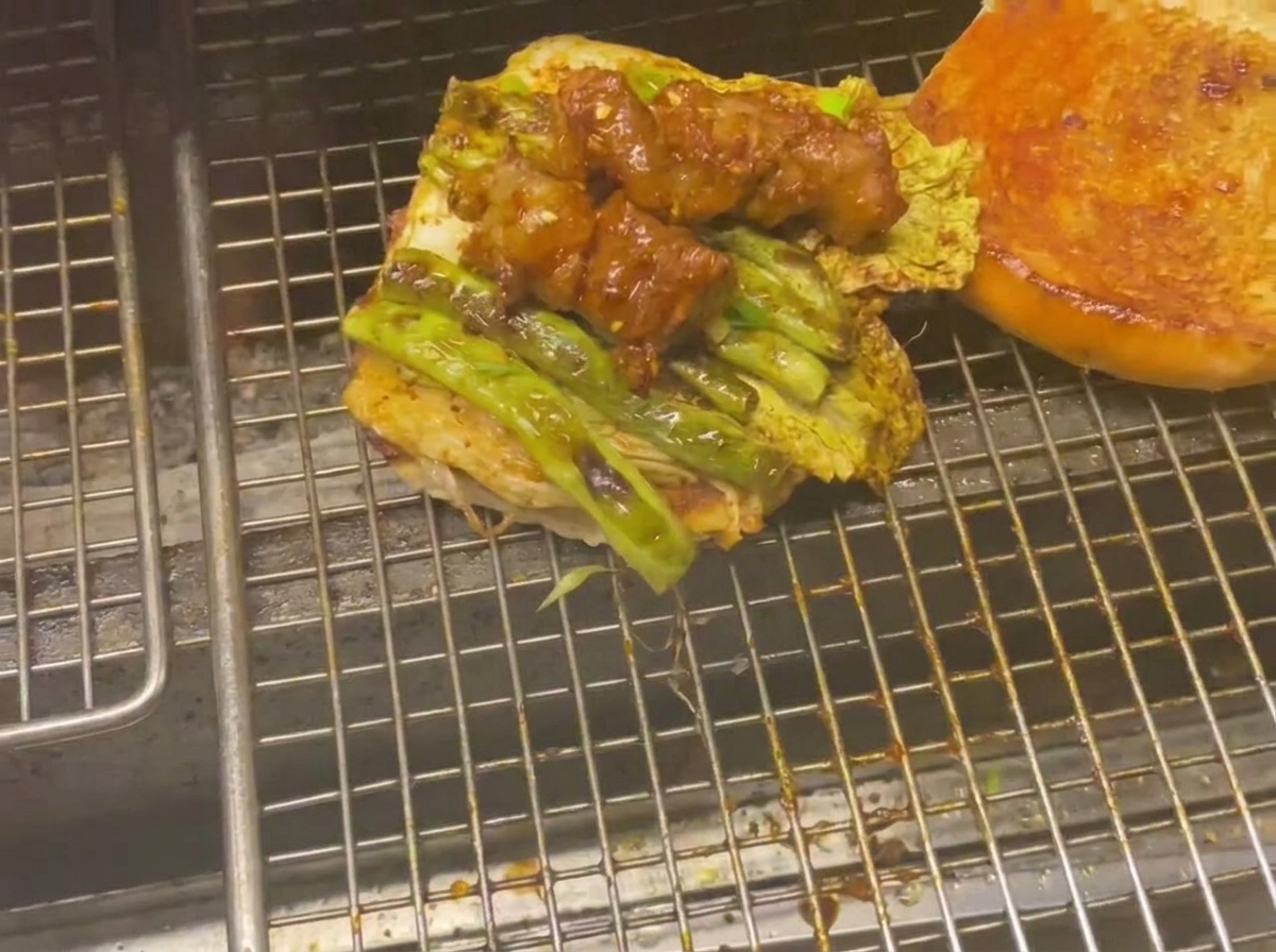 Base dun pain à burger surmontée de légumes grillés et de brochettes de viande glacées sur la grille.