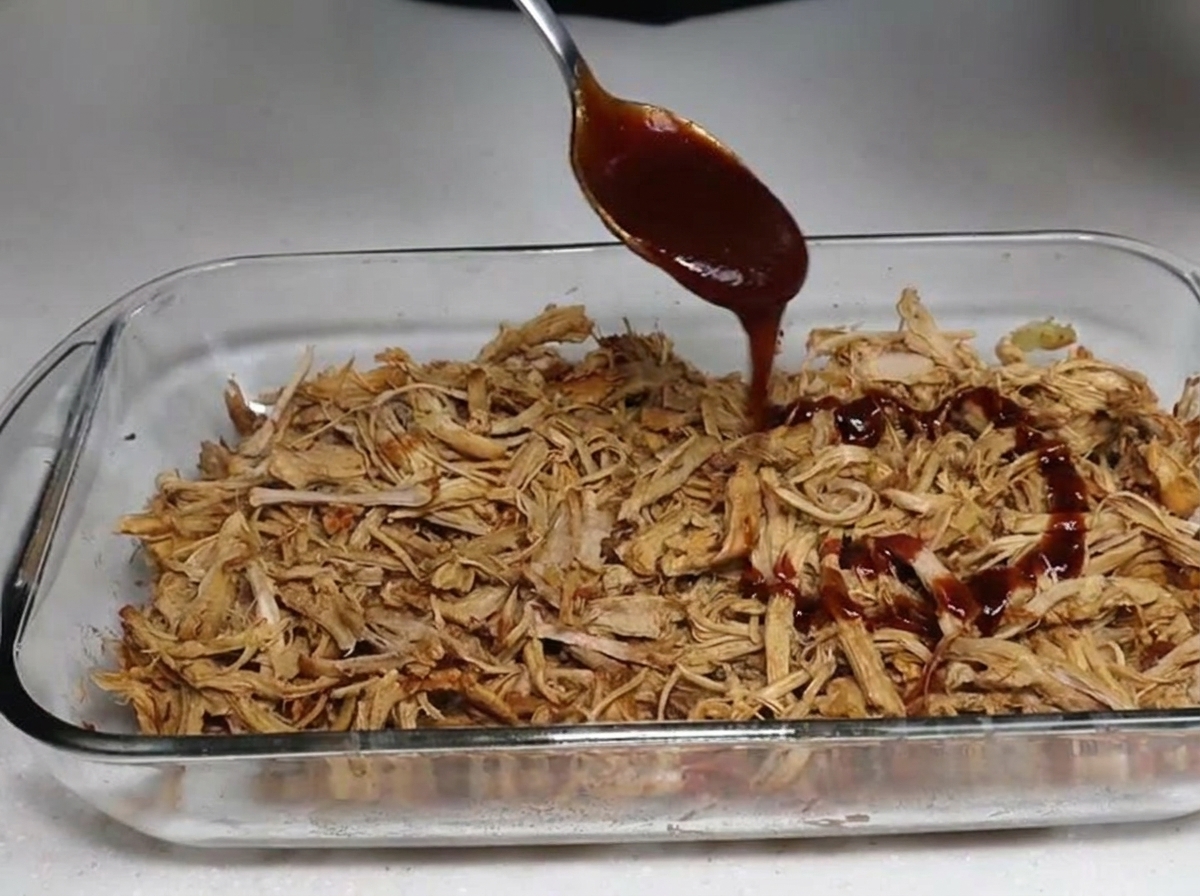 Sauce BBQ versée sur le porc effiloché fumé.