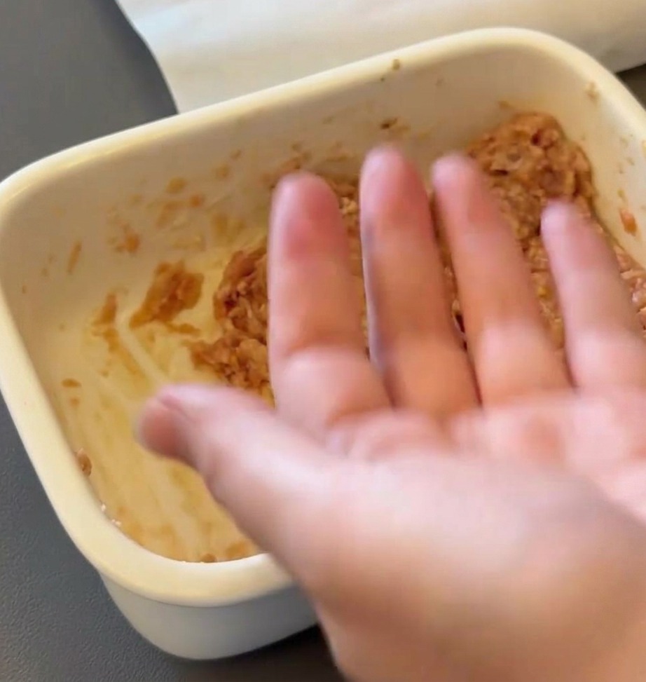 Une main façonnant un mélange de bœuf haché cru en une galette ronde.