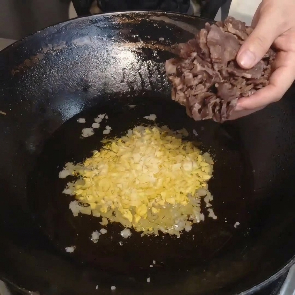 Tranches de bœuf séché à la vapeur transférées du bol dans le wok chaud.