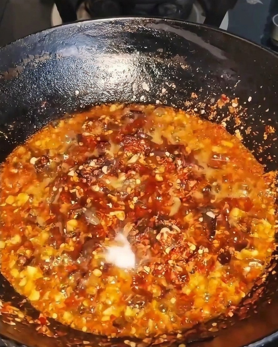 Sauce liquide sombre versée dans le wok grésillant.