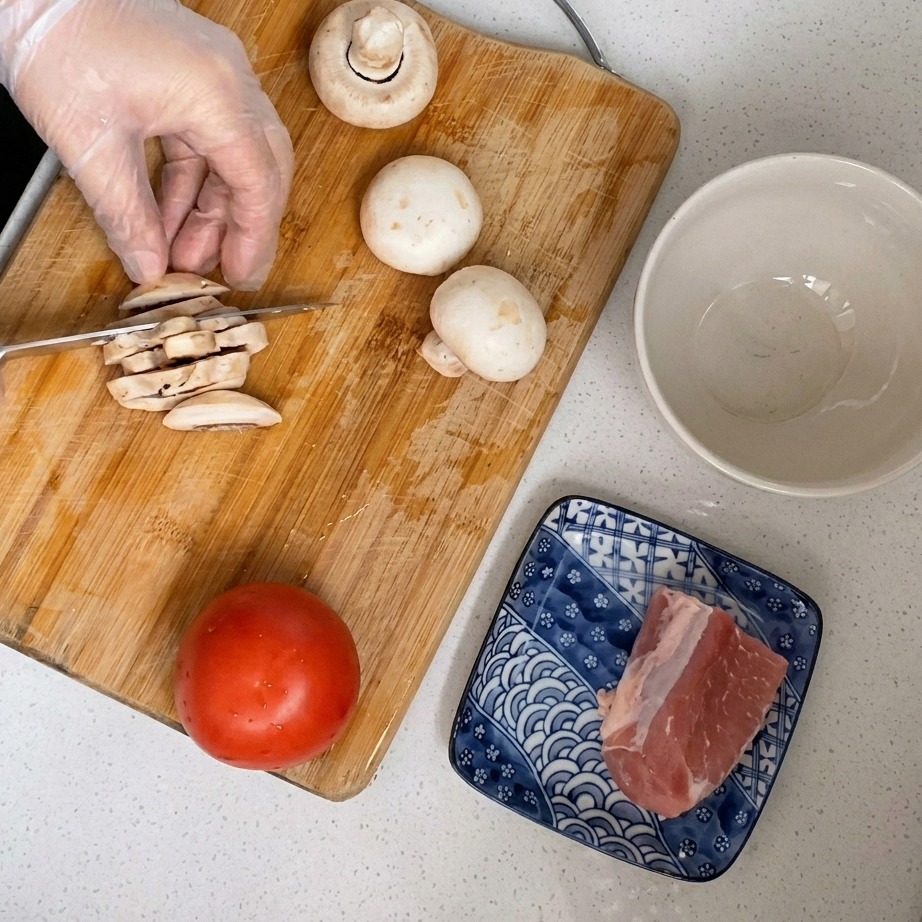 Des champignons de Paris frais coupés en fines tranches sur une planche en bois.