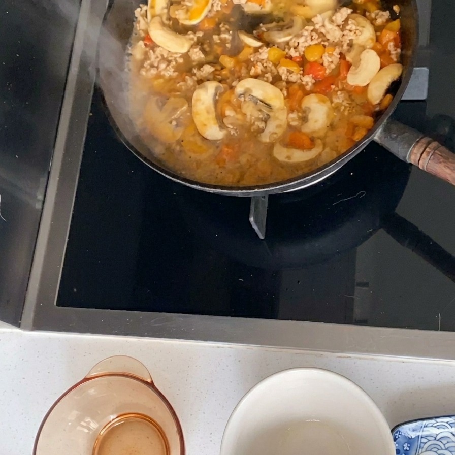 Une sauce frémissante à base de porc haché, de champignons et de tomates dans une poêle noire.