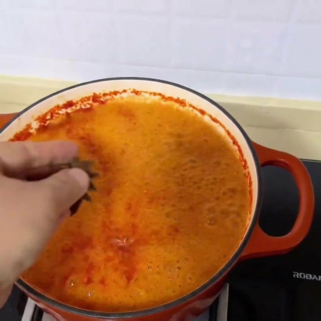 Trois gousses danis étoilé jetées dans la soupe de palourdes frémissante dun rouge vif.