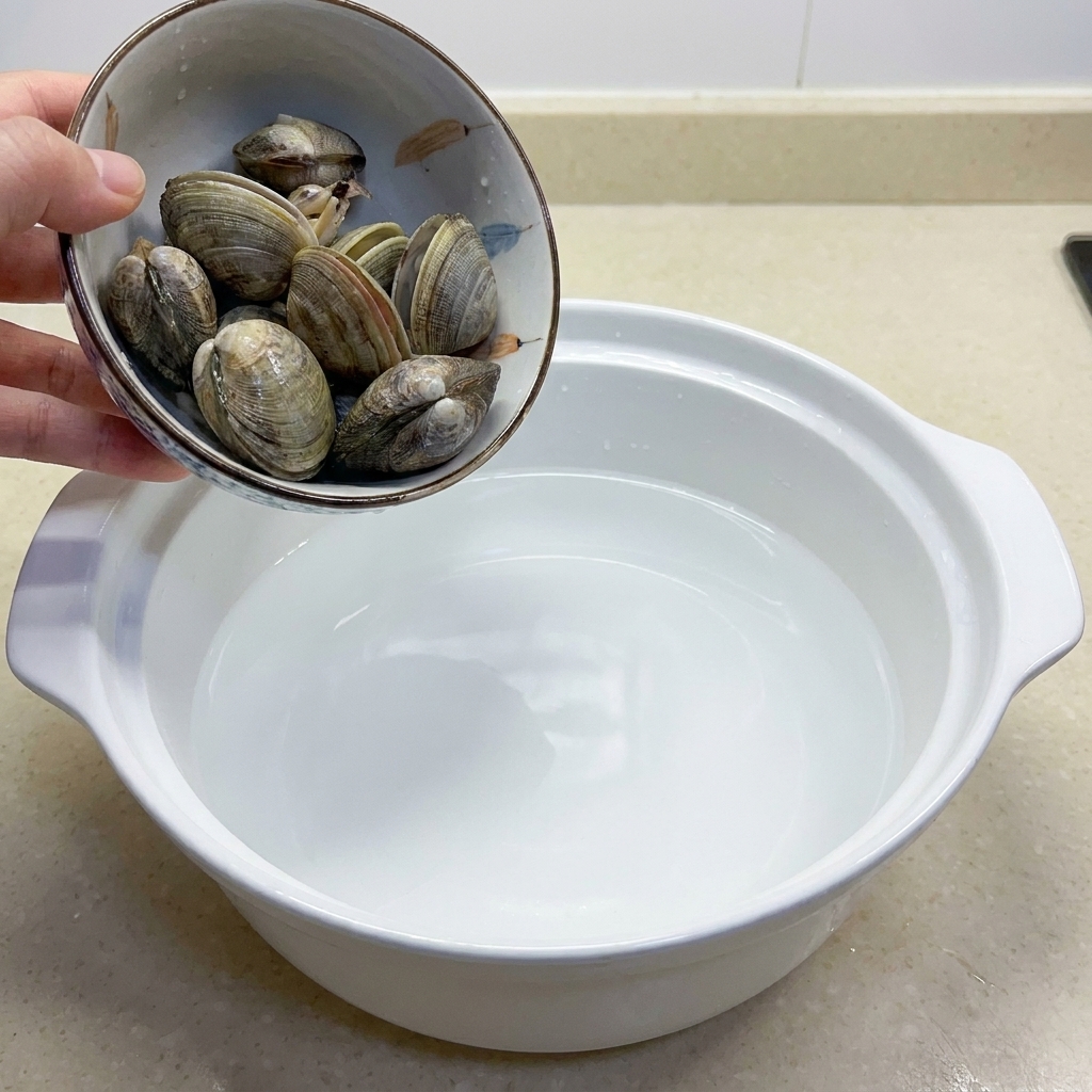 Un bol contenant plusieurs palourdes crues prêtes à être cuites.