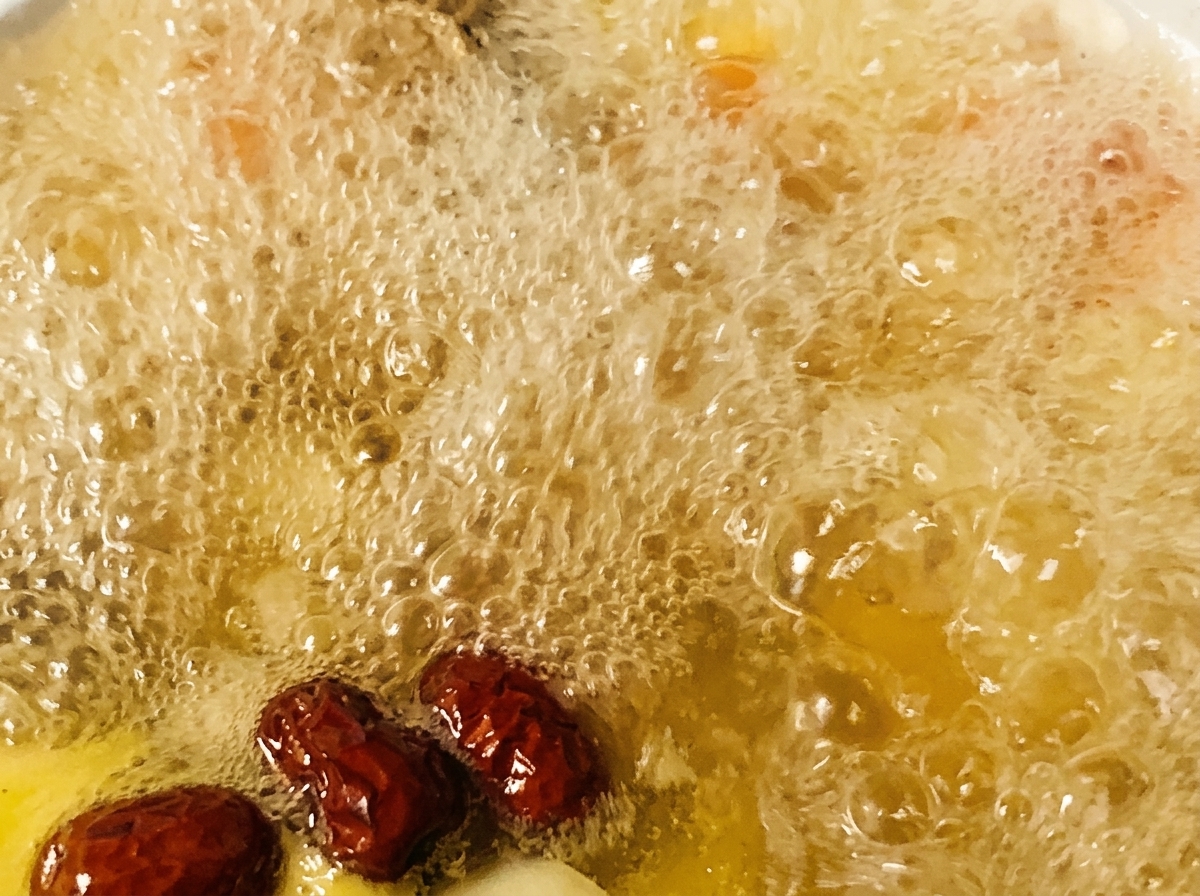 Ajout de dattes rouges et dassaisonnements dans une marmite de soupe de poulet bouillonnante.