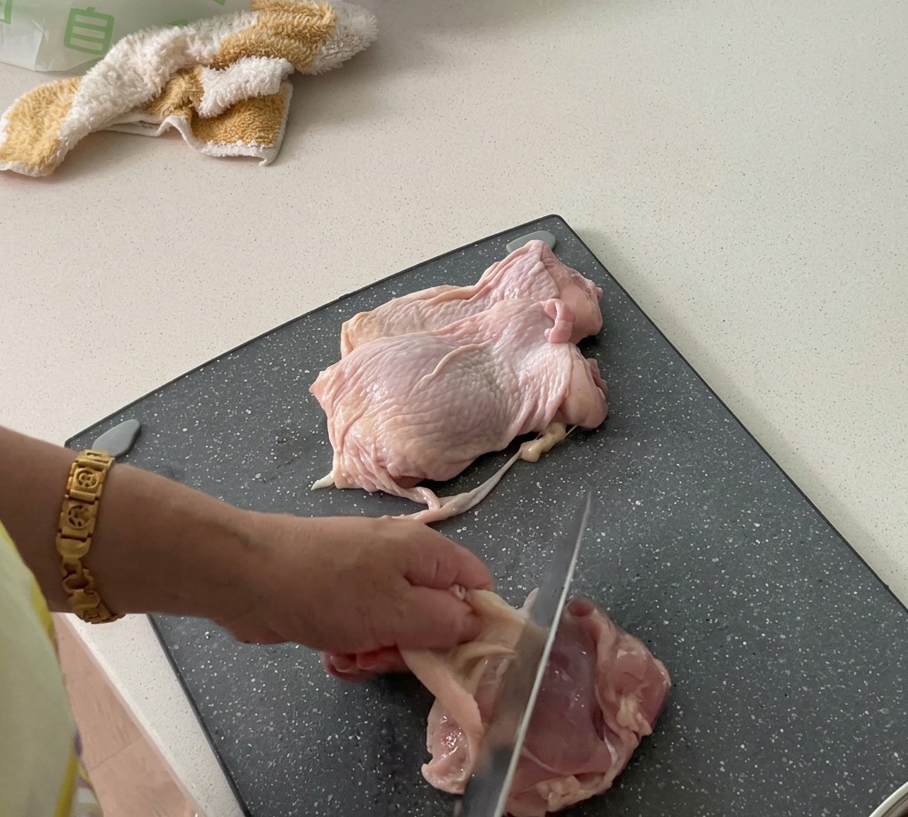 Hauts de cuisse de poulet en cours de préparation : retrait de la peau et découpe de la chair.