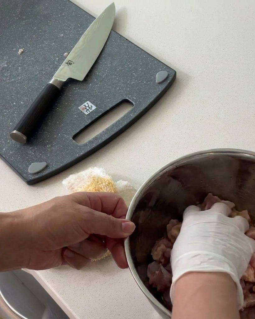 Le poulet coupé en dés mélangé avec les assaisonnements dans un bol en métal.