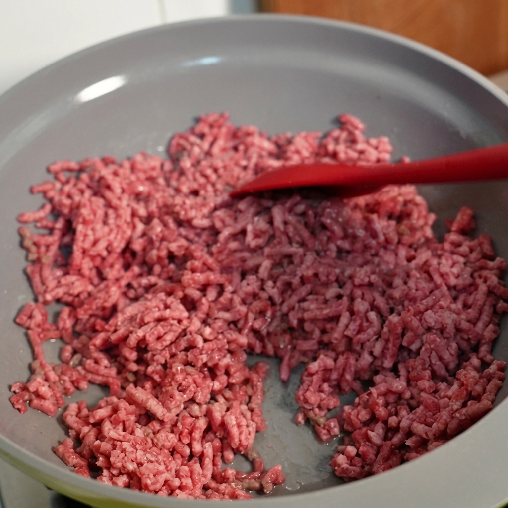 Du bœuf haché remué dans une poêle, montrant une texture bien dorée.