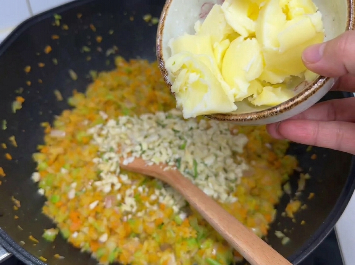 Gros morceaux de beurre ajoutés dun bol sur les légumes et lail haché dans un wok.