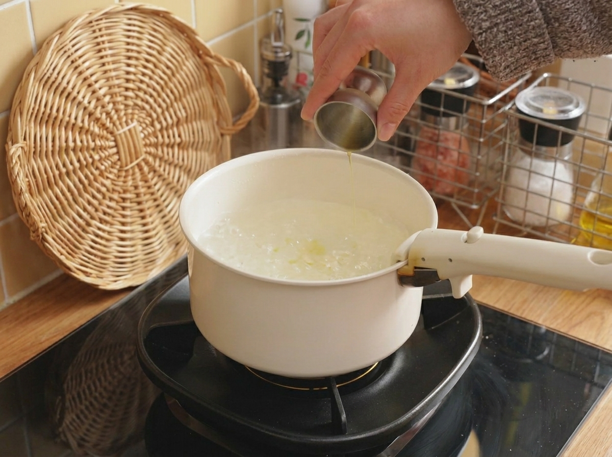 Huile versée depuis une petite tasse à mesurer en métal dans une marmite deau bouillante.