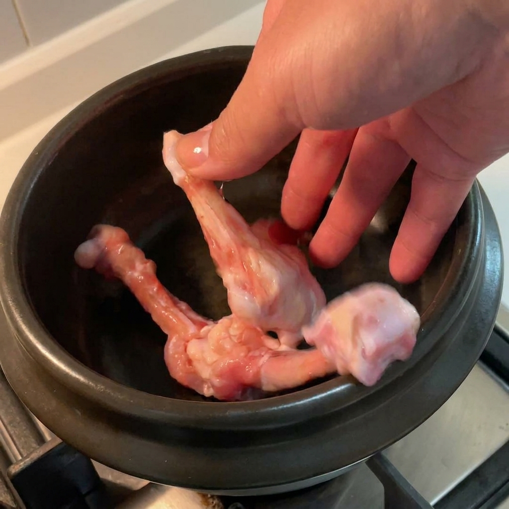 Os de poulet disposés dans une marmite en céramique noire.