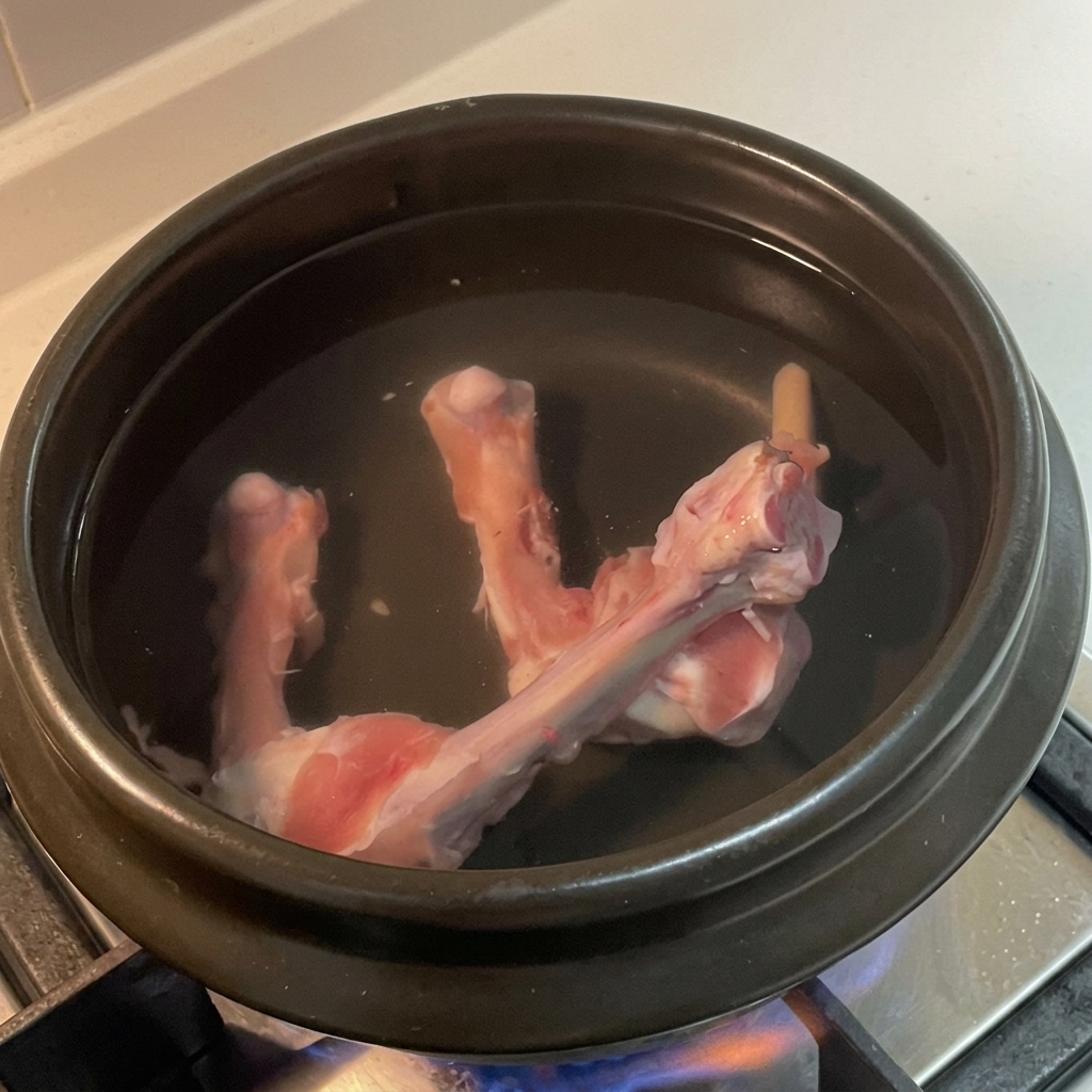 Tranches de gingembre, grains de poivre et feuille de laurier dans leau avec les os.