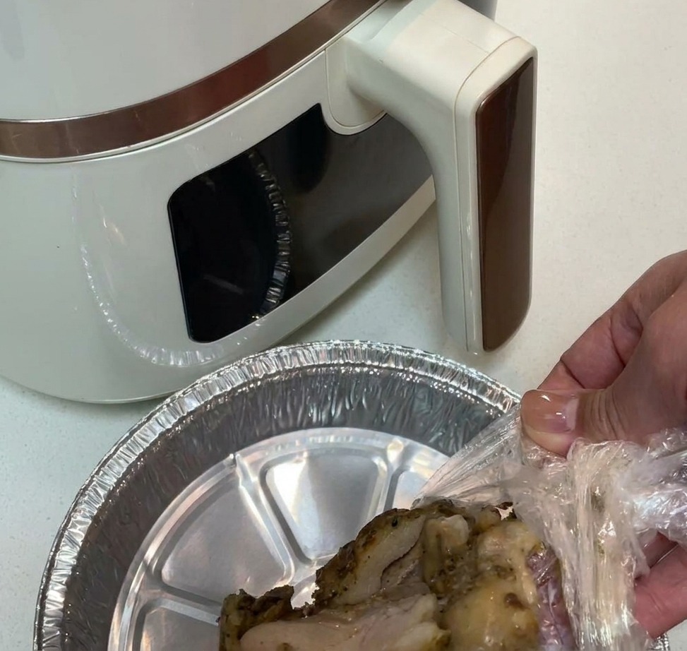 Morceaux de cuisses de poulet assaisonnés dans un panier de friteuse à air tapissé daluminium.