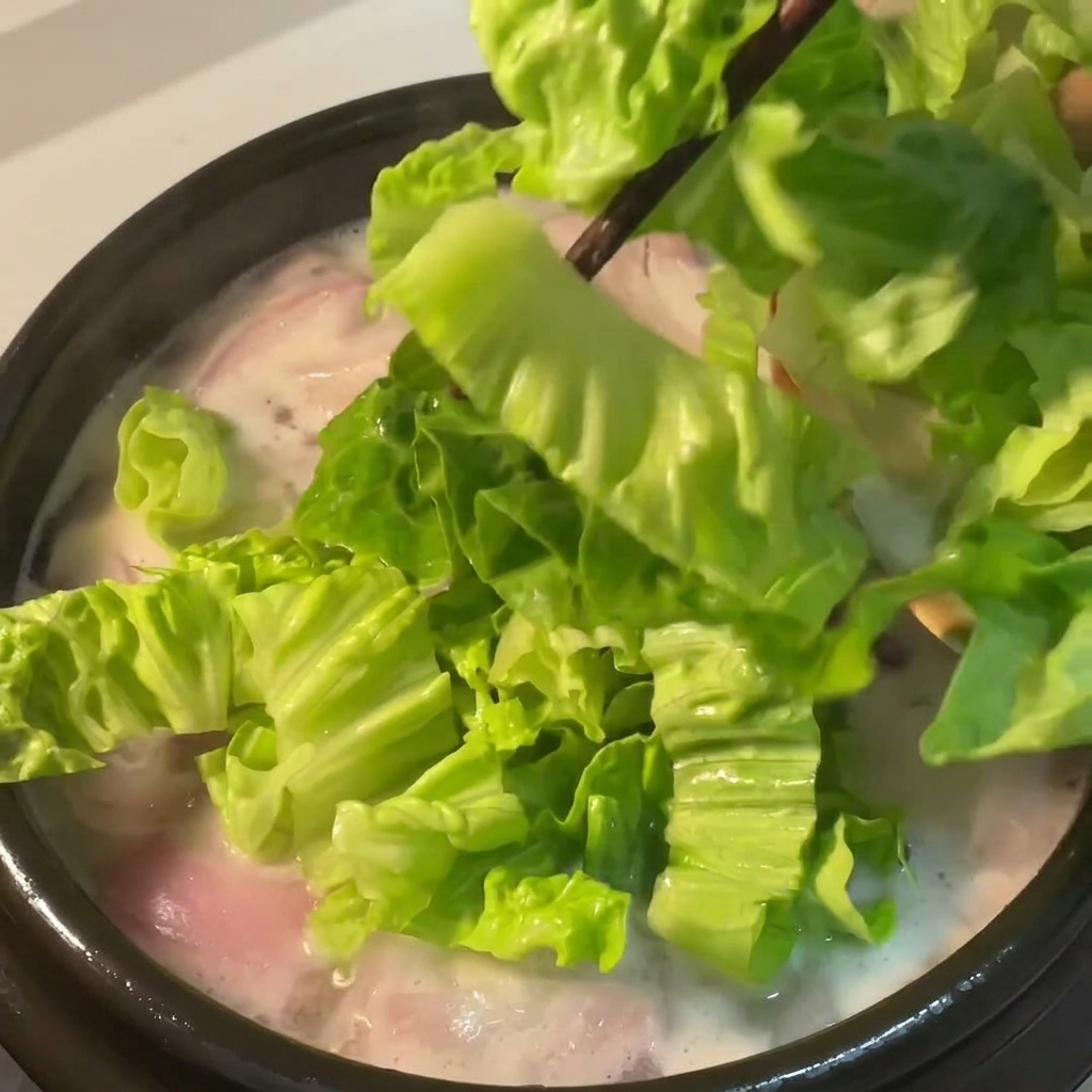 Laitue verte fraîche ajoutée dans la soupe frémissante.