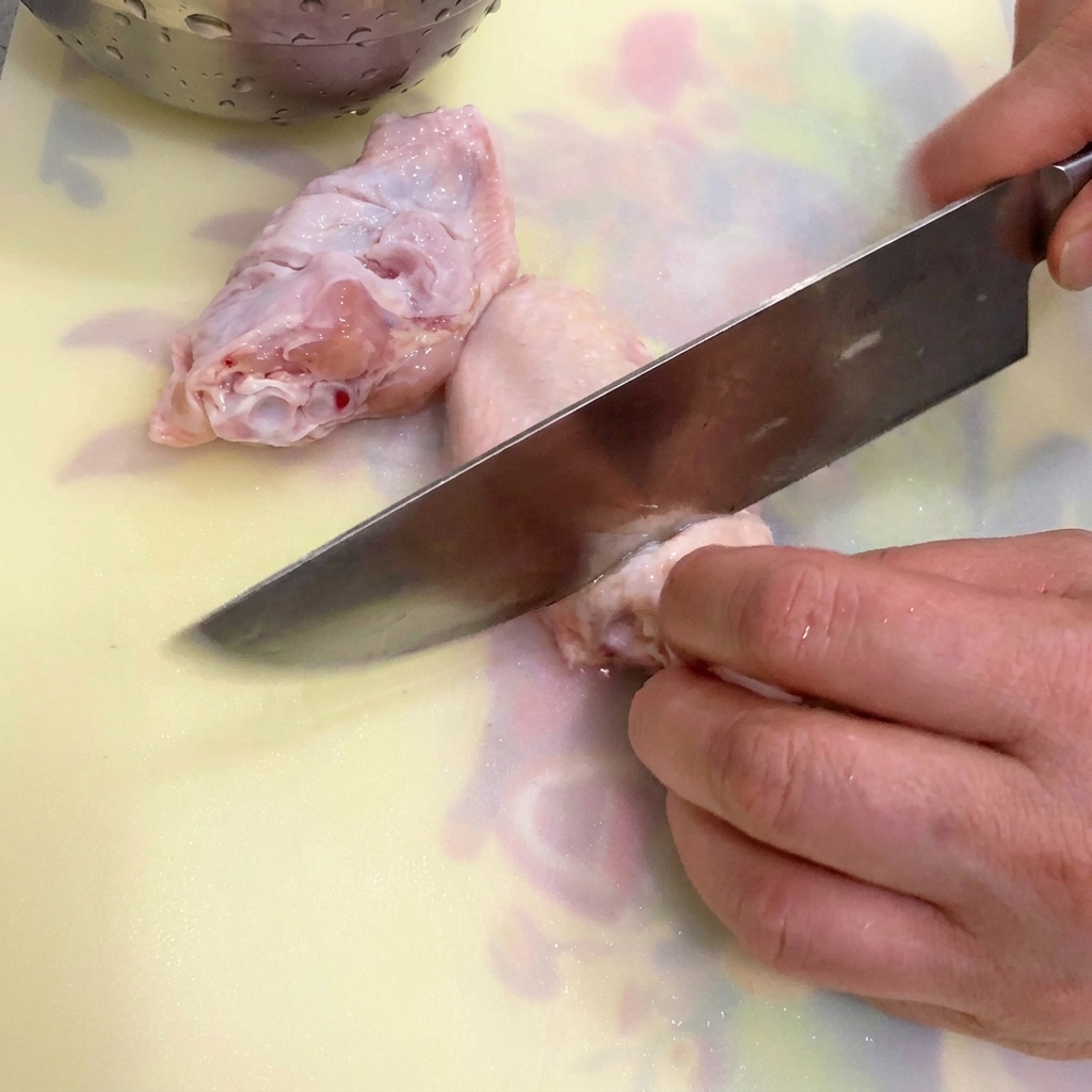 Ailes de poulet, gingembre et oignon vert dans une casserole deau froide prêts à être blanchis.
