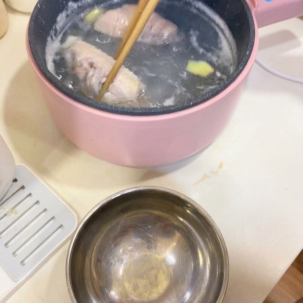 Des baguettes retirant les ailes de poulet blanchies de la casserole.