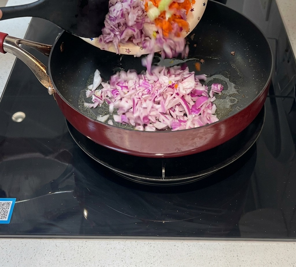 Des oignons, des carottes et du céleri finement coupés en dés versés dans une poêle pour être sautés.
