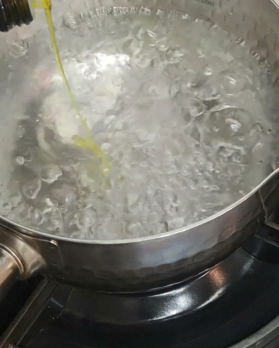 Huile dolive versée dans une grande casserole deau bouillante.