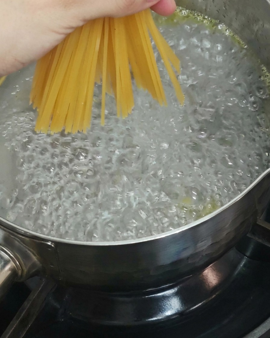 Des spaghettis secs plongés dans une casserole deau bouillante.