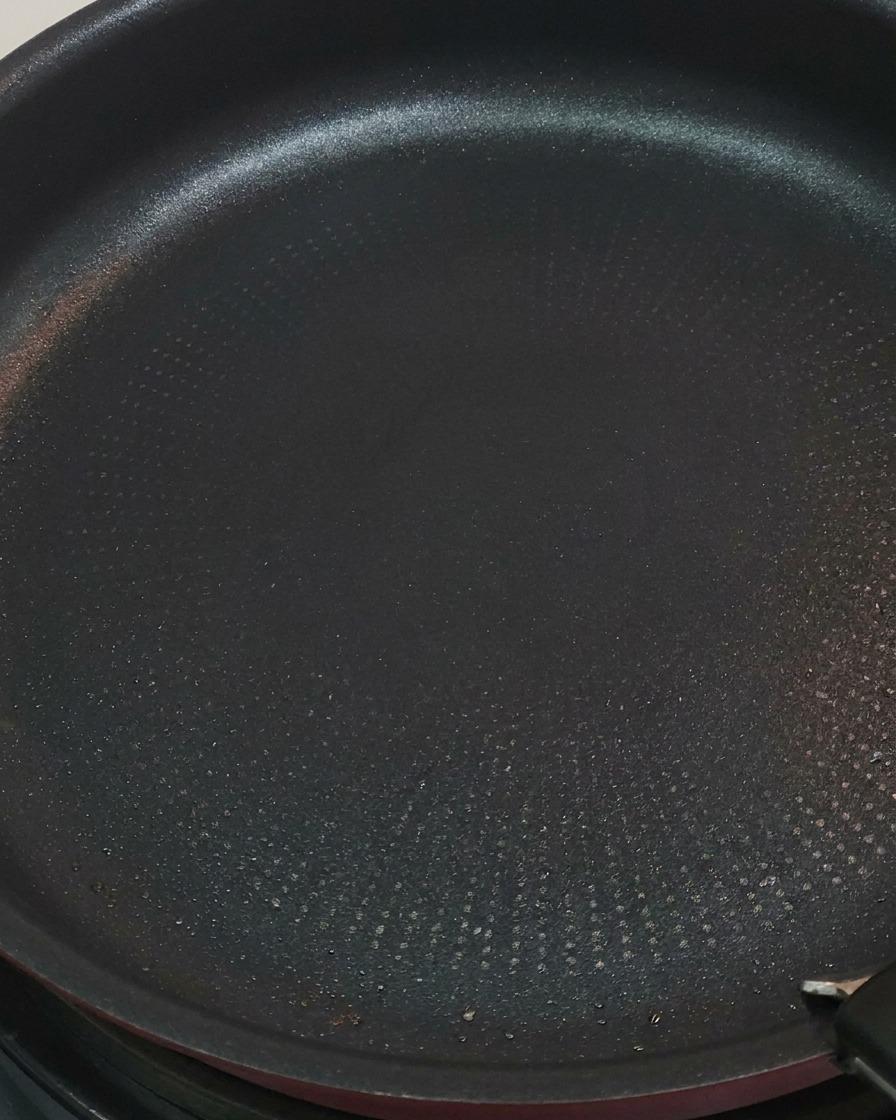 Pinces retournant les morceaux de poulet dorés dans la poêle.