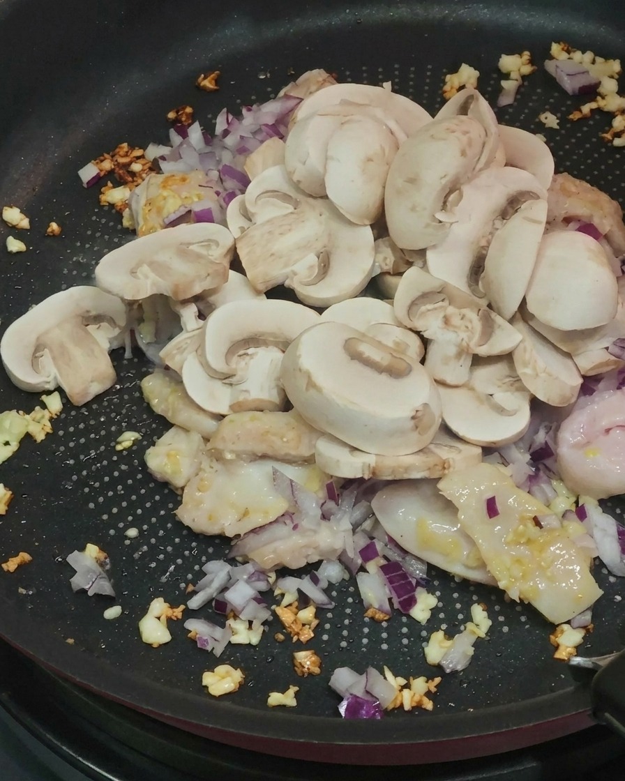 Champignons tranchés ajoutés à la poêle.