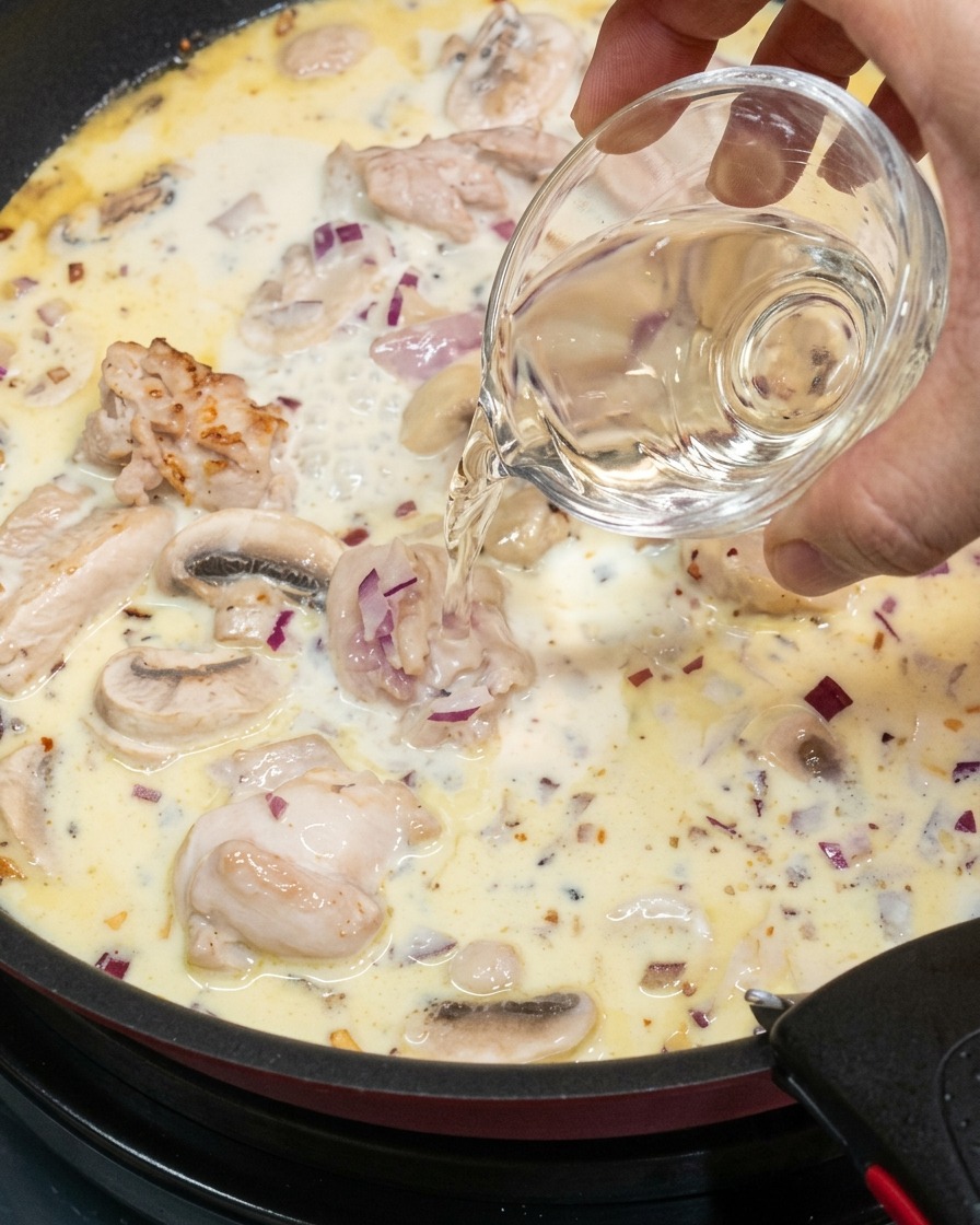 Verser un filet de vin blanc dans la sauce mijotante.
