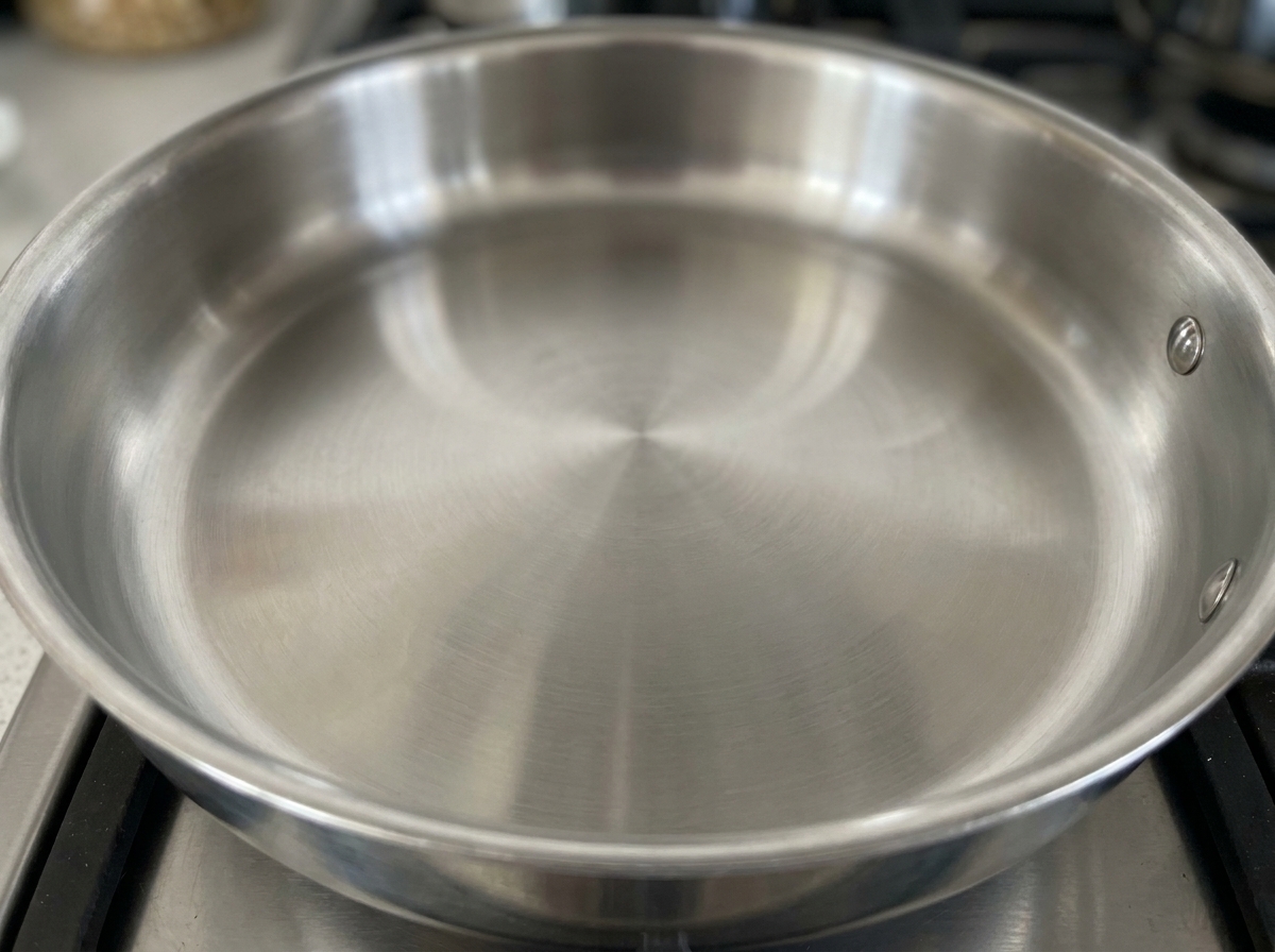 Grains de poivre noir chauffant dans une poêle sèche sur une plaque de cuisson.
