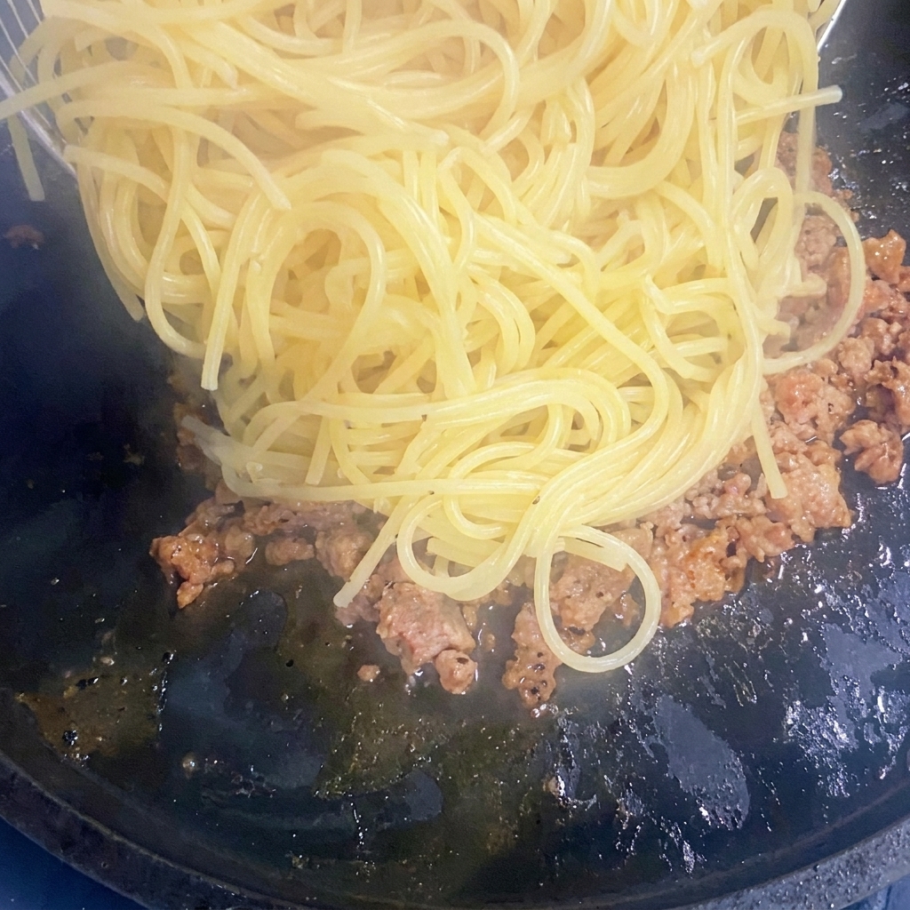 Spaghetti cuits ajoutés dans une poêle avec le bœuf haché doré.