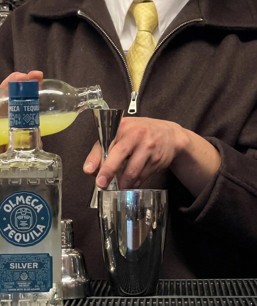 Du jus de citron vert frais est versé dans un doseur au-dessus dun shaker à cocktail.