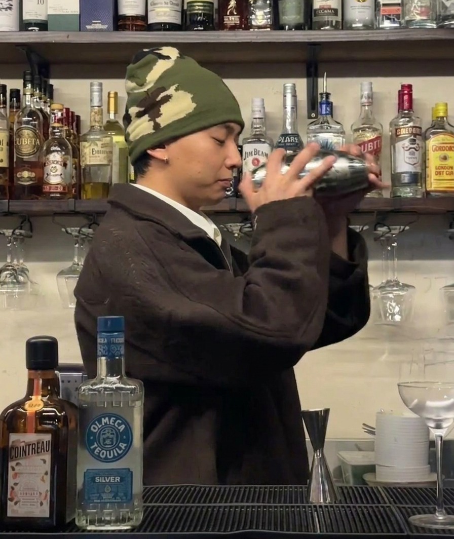 Un barman secouant vigoureusement un shaker pour refroidir les ingrédients dun cocktail.