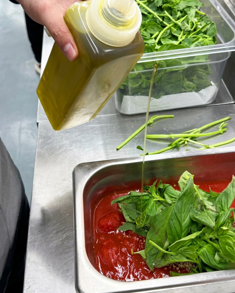 Huile dolive versée dans un récipient contenant les ingrédients de la sauce.