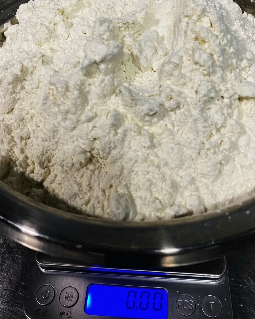 Un tas de fine farine 00 dans un bol en inox sur une balance.
