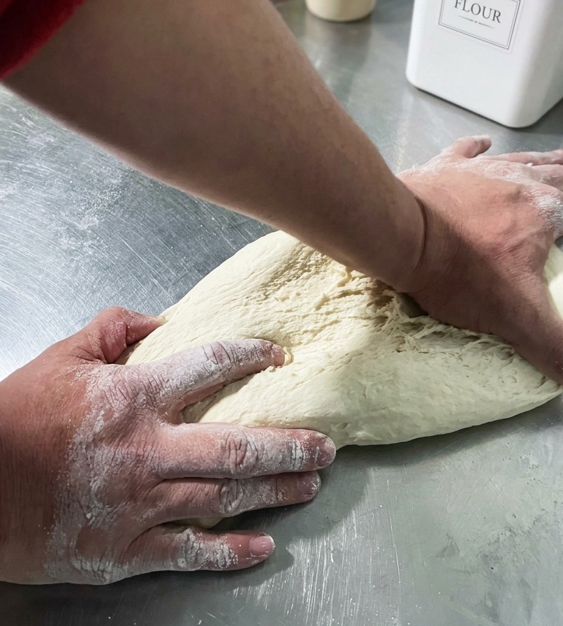 Mains formant une boule de pâte lisse sur un plan de travail.