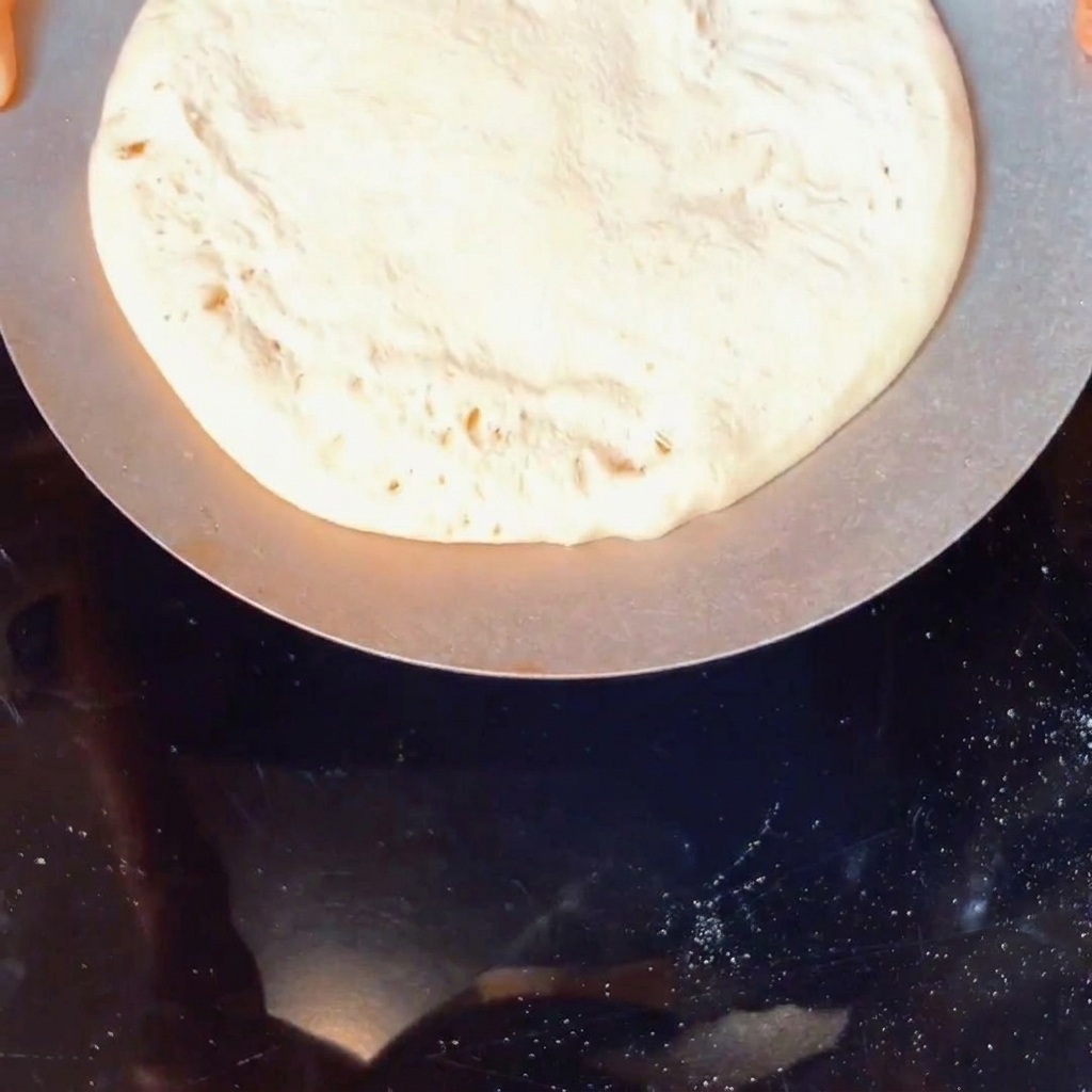 Une boule de pâte à pizza fraîche recouverte de semoule de maïs dans un récipient.