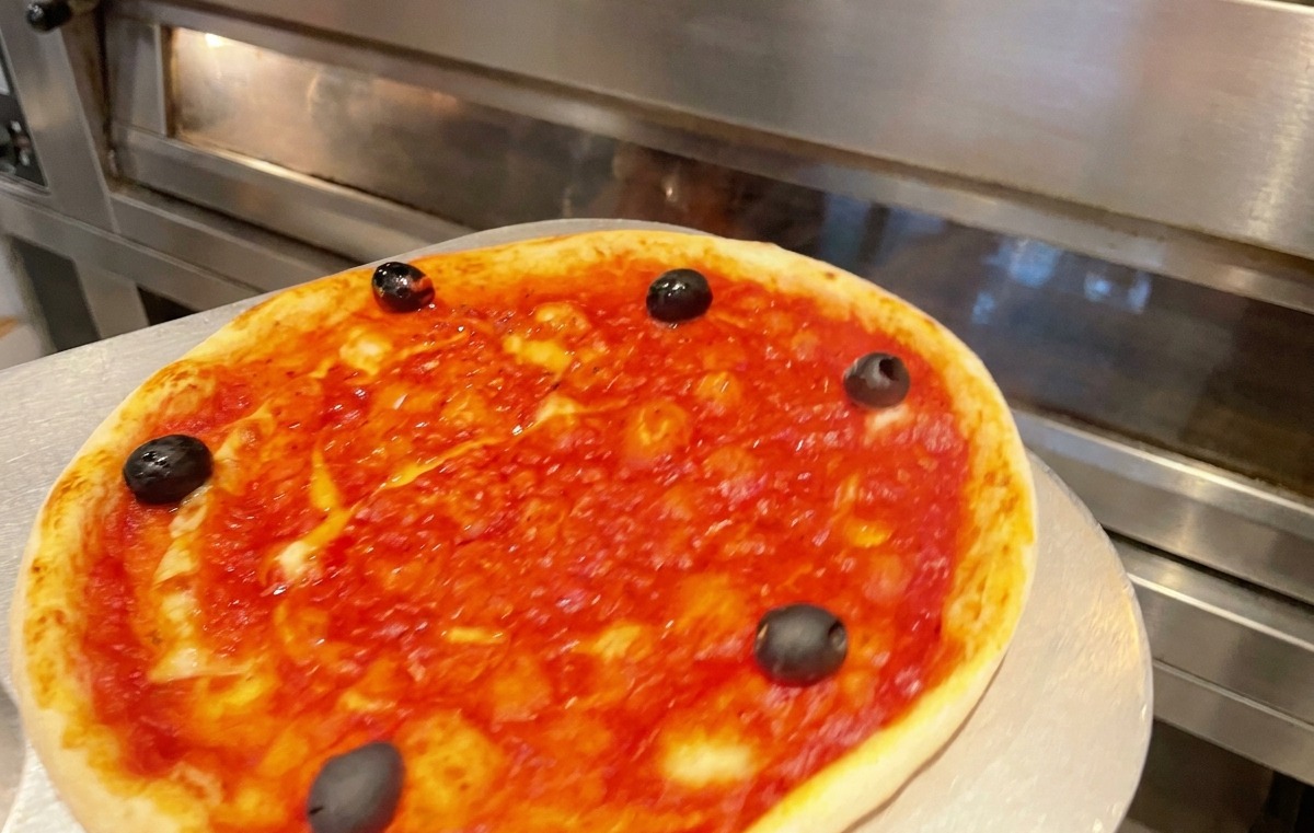 Un moule à pizza glissé dans un four chaud professionnel.