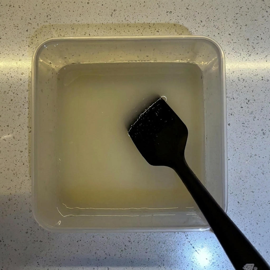 Farine versée dans un récipient transparent contenant le mélange deau et de levure.
