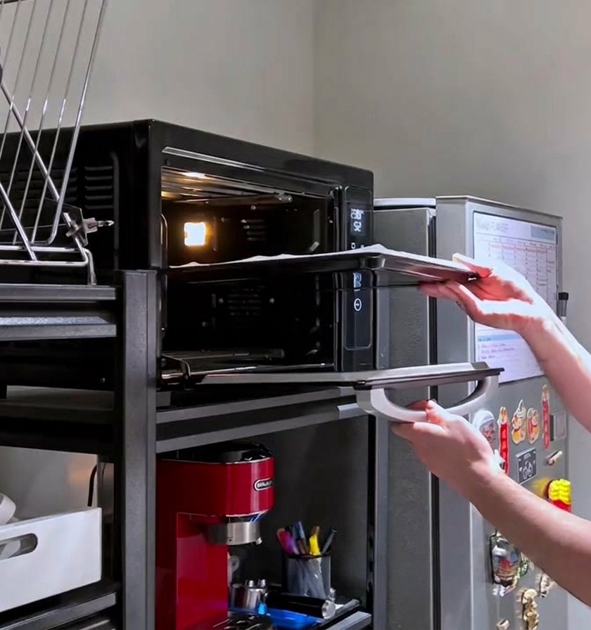 Une personne glissant une plaque avec la pâte à pizza crue et piquée dans un four domestique bien chaud.