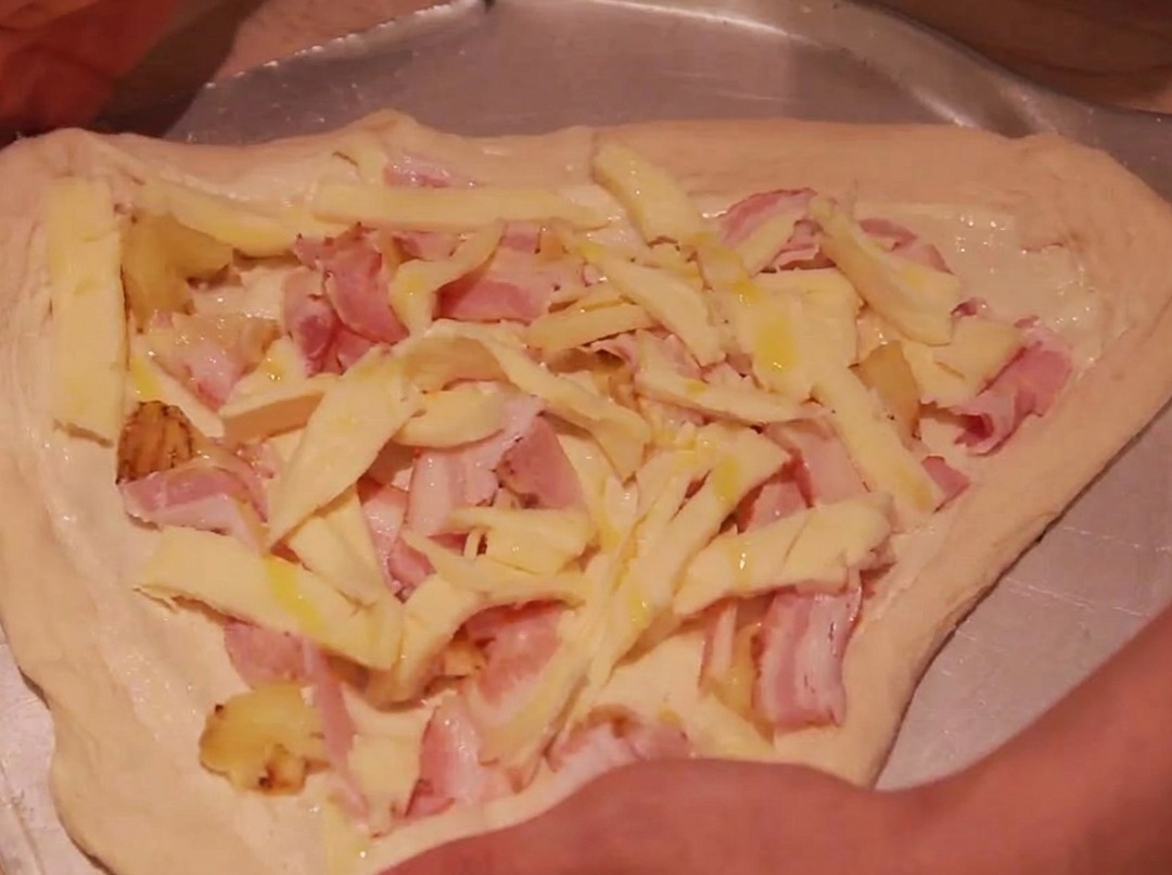 Les bords de la pâte à pizza repliés vers lintérieur pour enfermer la garniture.
