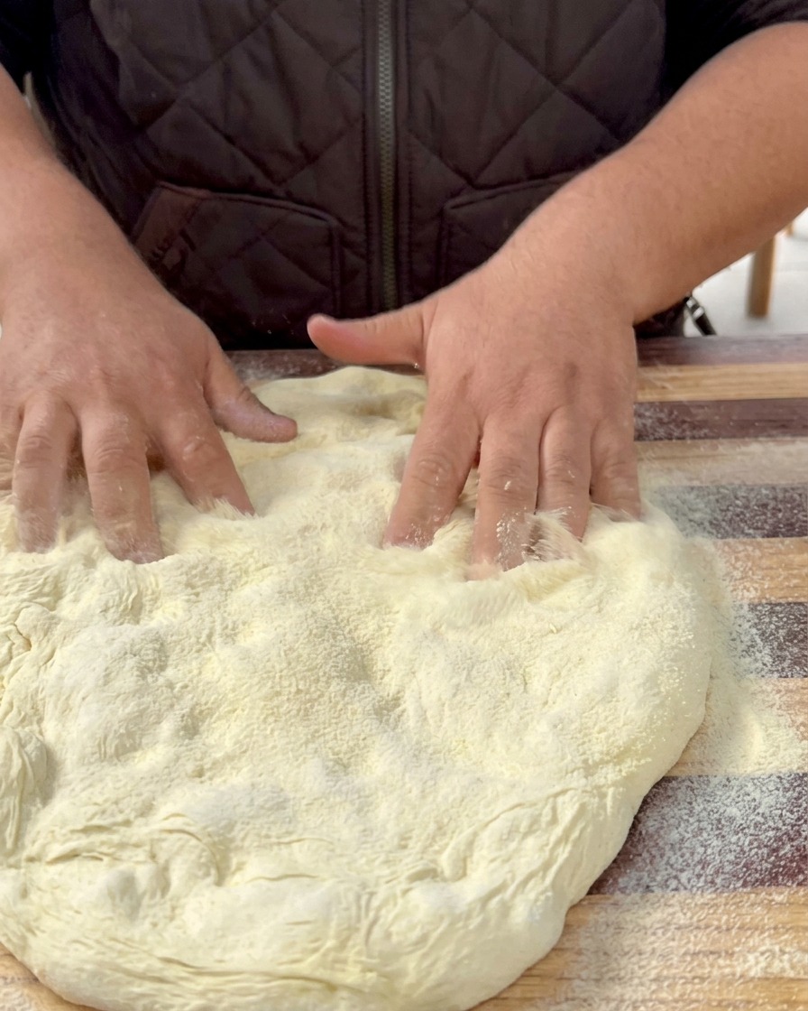 Pâte à pizza étalée reposant sur une plaque de cuisson recouverte de papier sulfurisé.