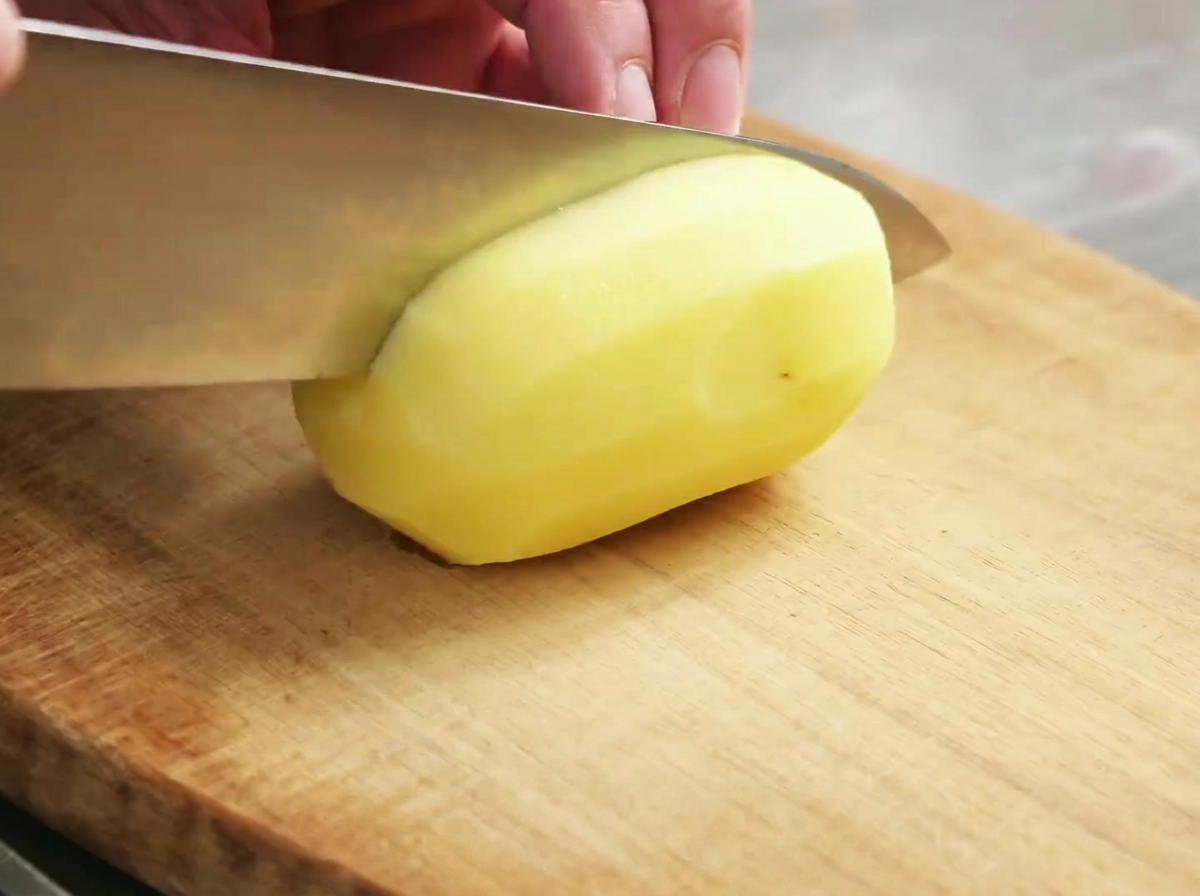 Morceaux de pommes de terre crus préparés sur une planche à découper en bois.