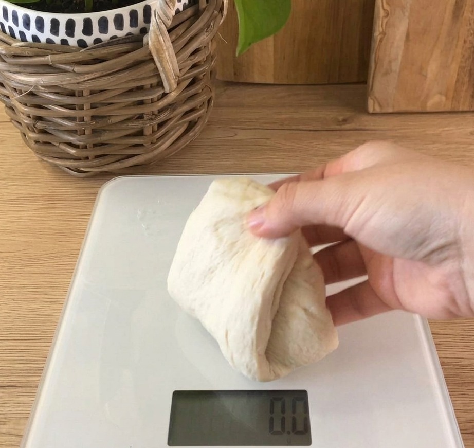 Une portion de pâte à pain souple et blanche posée sur une balance de cuisine numérique.