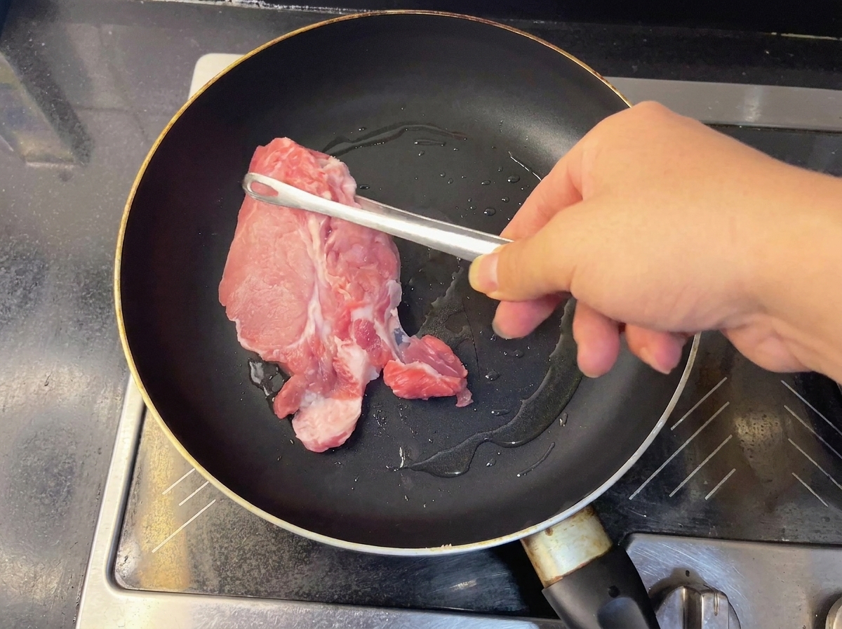 Deux morceaux déchine de porc crue saisis dans une poêle chaude.