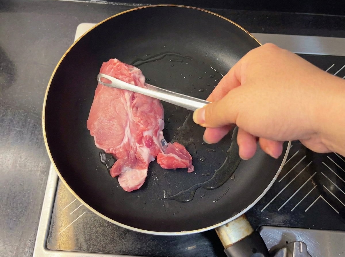 Morceaux de porc tendres et dorés retirés de la poêle avec des pinces.