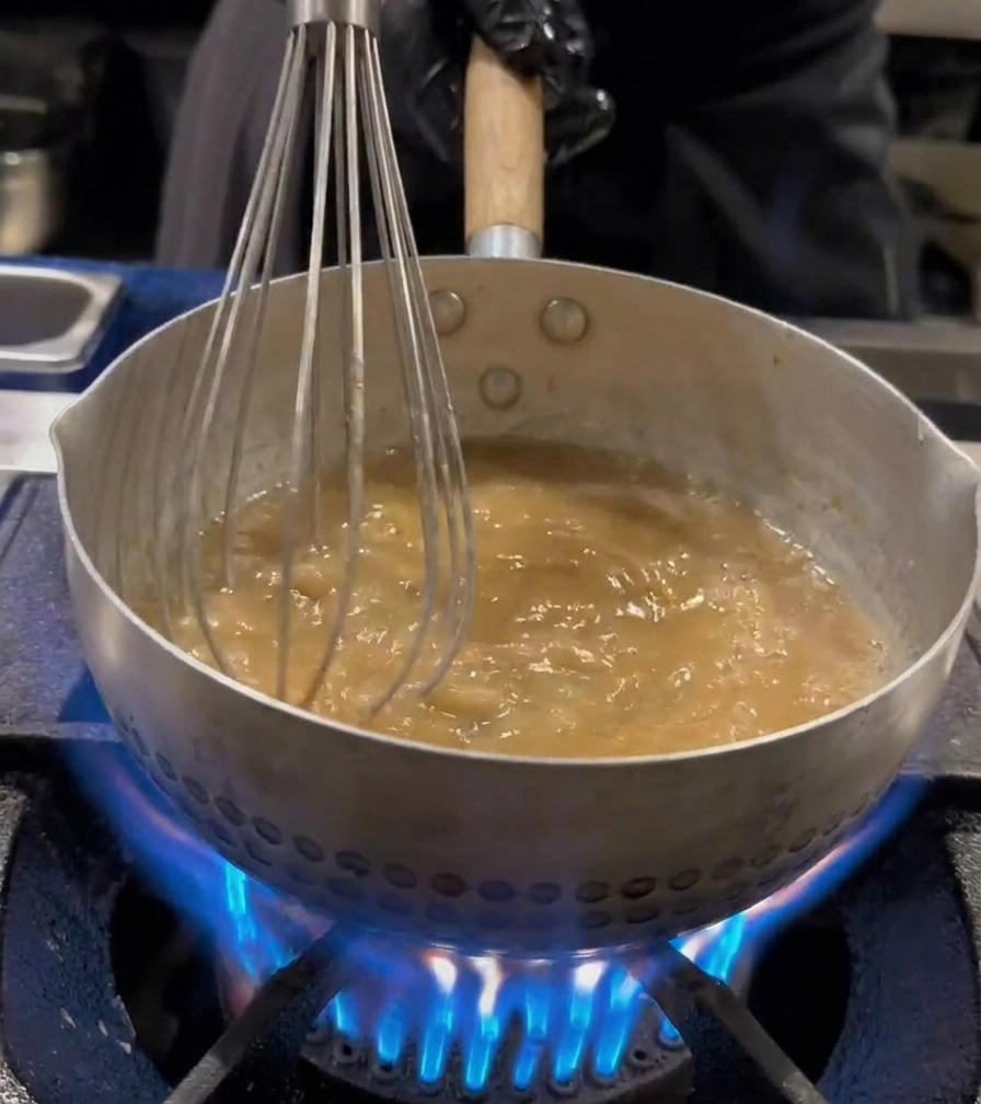 Des nouilles ramen mélangées avec un fouet en fil métallique dans une casserole deau bouillante.