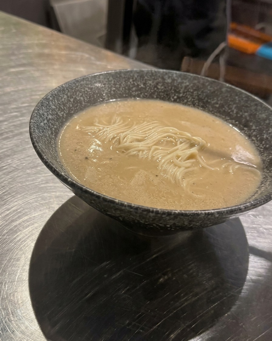 Une cuillerée de viande hachée assaisonnée déposée au centre dun bol de ramen avec bouillon.